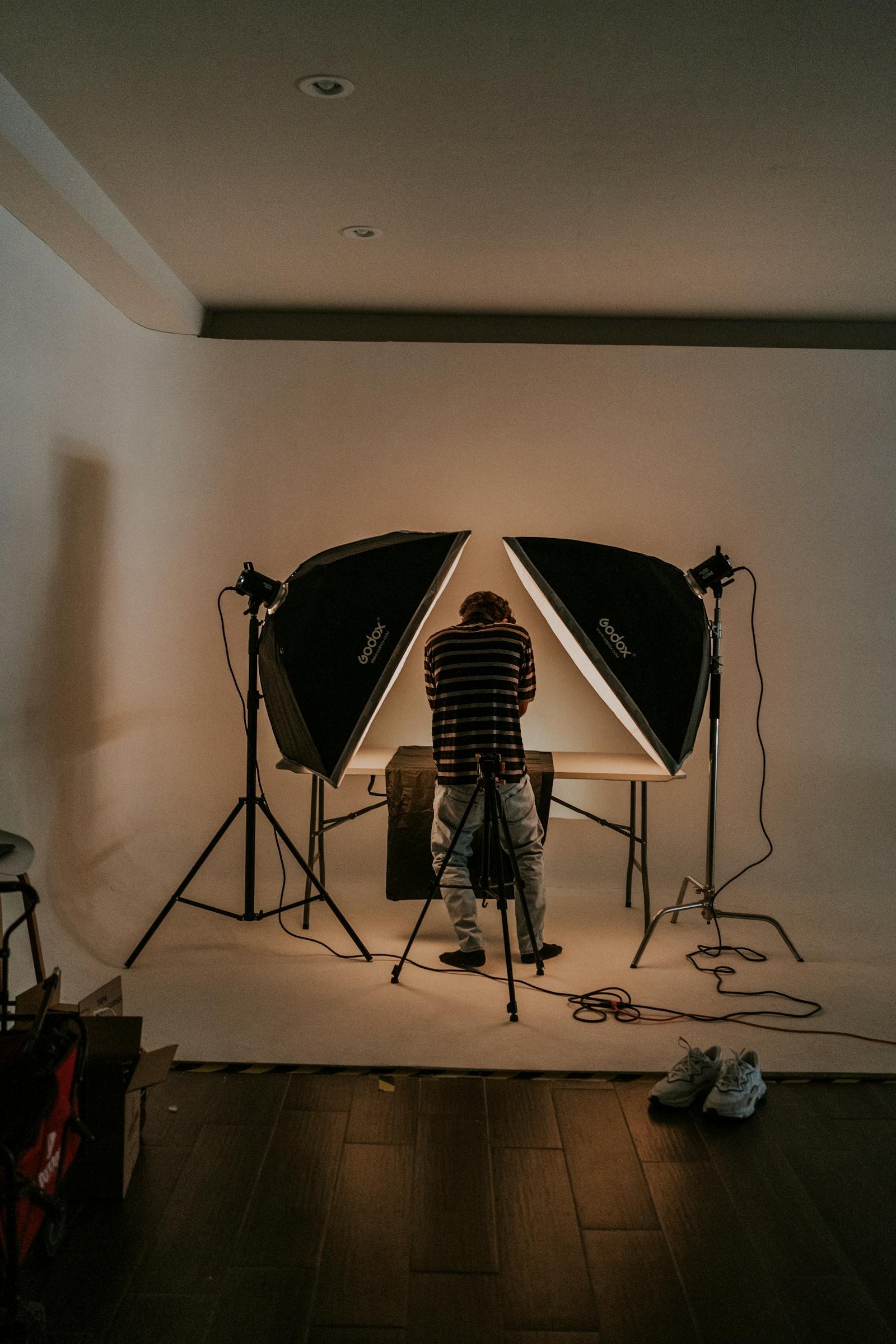 A single Profoto strobe firing through a 4×6 silk on a Brooklyn rooftop at golden hour, two stylists holding the frame against the wind.